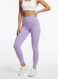 Person wearing lavender leggings and a white sports bra on a light gray background