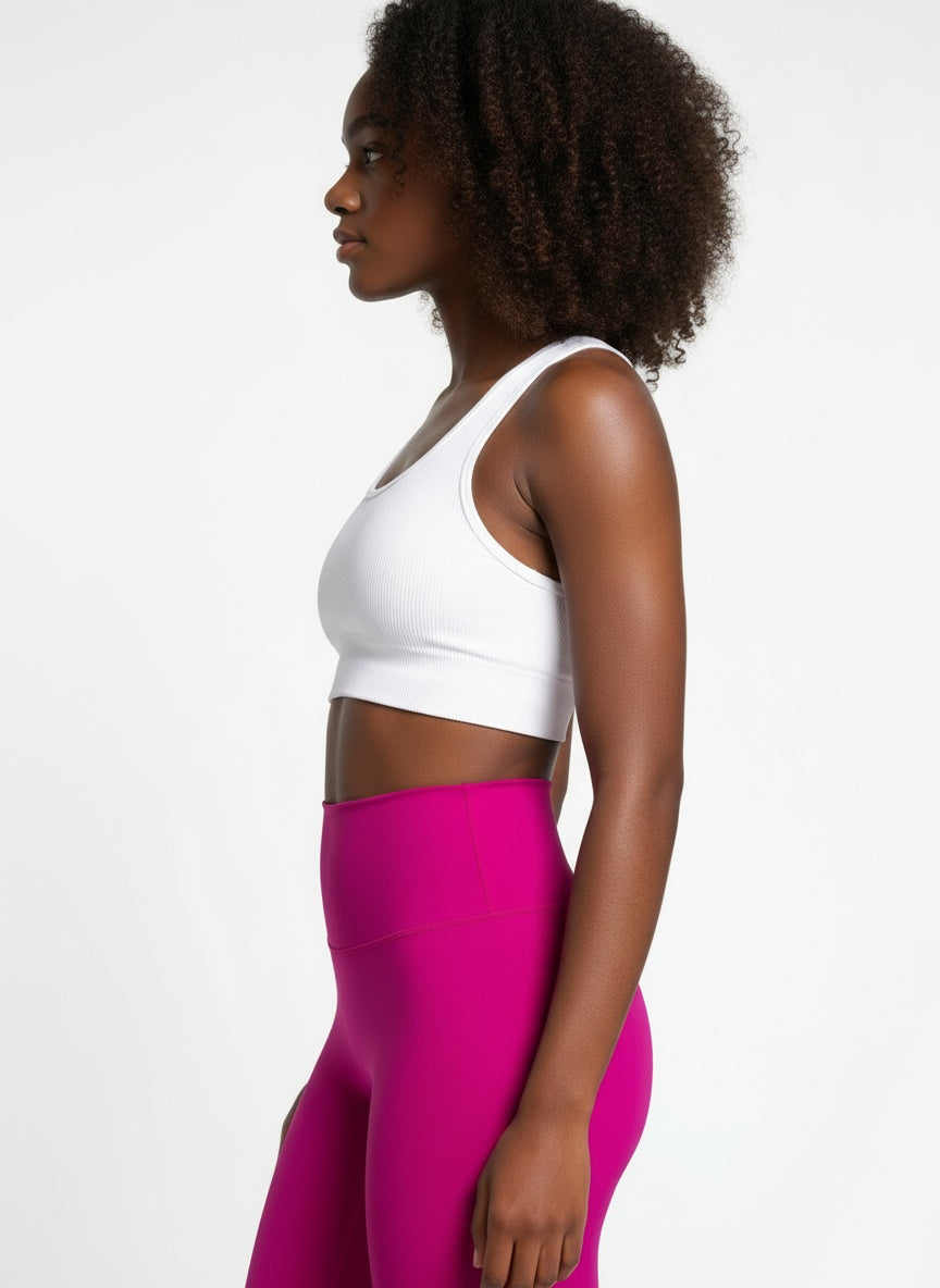 Woman wearing a white sports bra and pink leggings on a white background